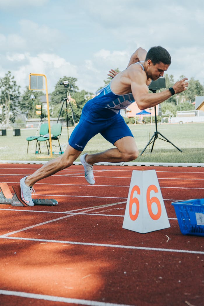 Home A determined male athlete sprints from starting blocks on an outdoor track.